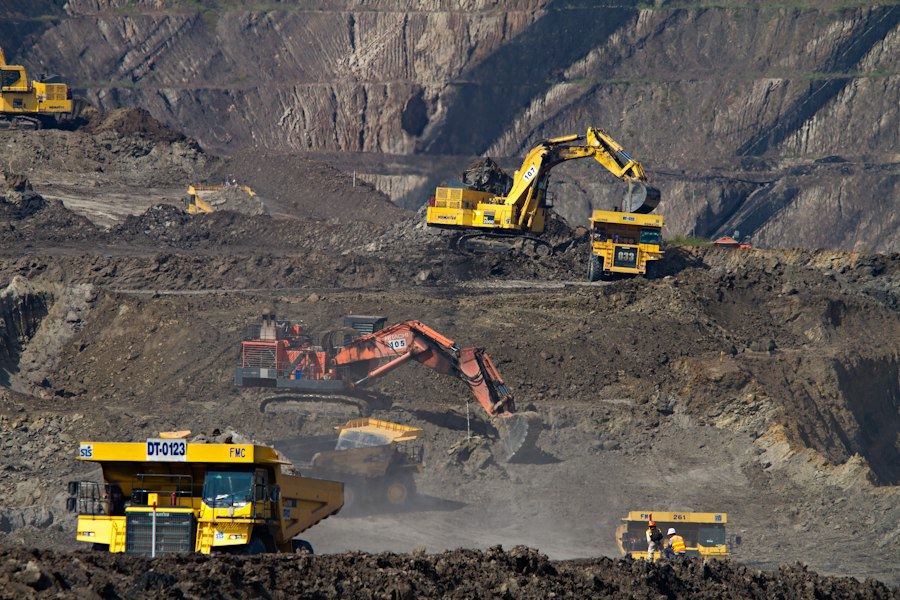 Excavators and haul trucks at an open-pit mine site with IT/OT systems